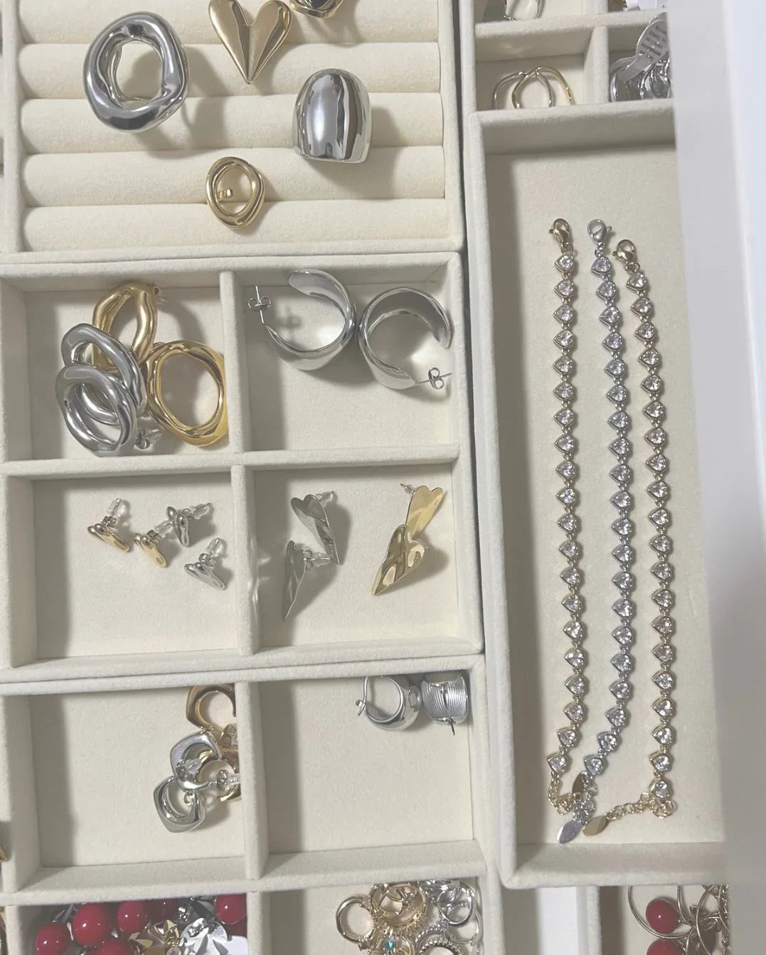 Vassoi in velluto beige con orecchini argento e oro e bracciali con pietre a cuore Les Soeurs 33