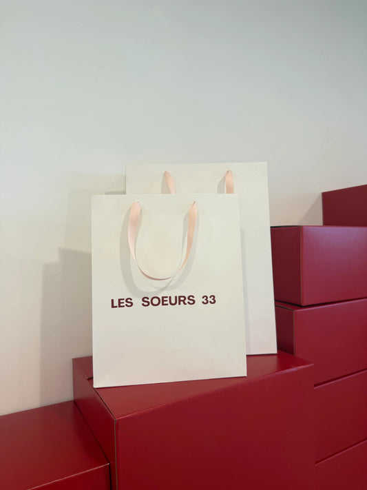 Buste e borsa bianca Les Soeurs 33 con manici rosa su scatole rosse impilate