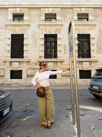 borsa Kim mini marrone coffee in ecoseude indossata con outfit maglia bianca pantalone beige e ballerine coffee in centro città